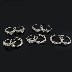 Detail view of adjustable silver rings featuring zircon leaf and star patterns on black mirror