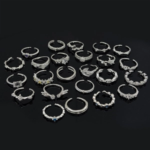 Macro shot of 22 silver rings with stars, leaves and gemstones on a black reflective base
