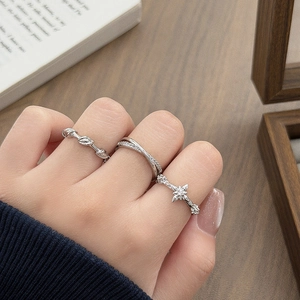 Close-up of three silver star and leaf zircon rings worn as a stylish stacked jewelry set