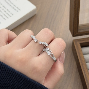 Detailed view of silver meteor rings with zircon stones on hands by a wooden box