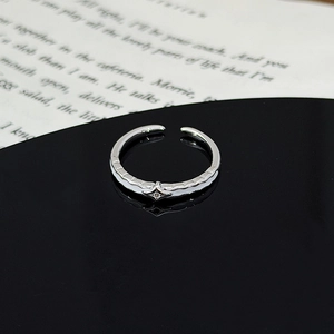Macro detail of silver adjustable star ring with zircon stone on reflective surface