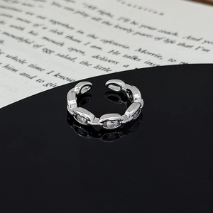Detailed view of silver chain link ring with sparkling zircon stone on a black surface