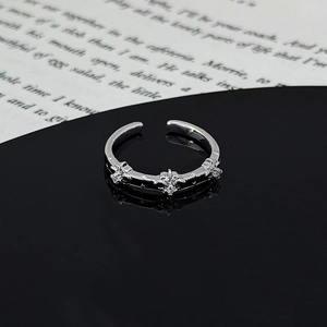 Macro shot of polished silver ring with cross patterns and zircon stones on black background