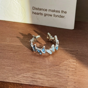 Macro view of adjustable silver ring featuring blue glitter butterfly charms and sparkles