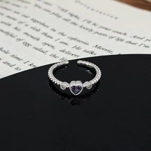 Macro shot of silver ring with purple heart gem, side diamonds and twisted band details