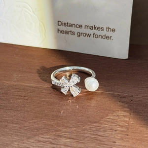Close-up of silver clover ring with sparkling cubic zirconia and a white pearl detail