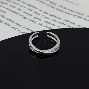 Macro shot of silver adjustable cross ring with pavé zircons on black mirror base