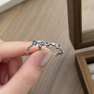 Detail of adjustable silver star leaf rings with blue zircon stones on a wooden box