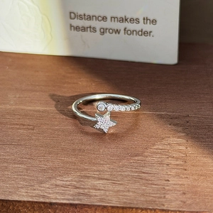 Macro shot of silver star-shaped adjustable ring with cubic zirconia on wood background