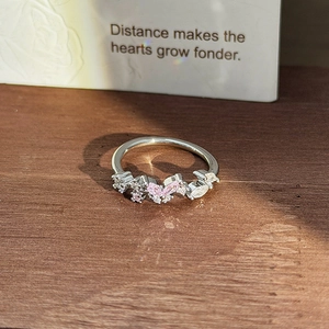 Macro view of butterfly ring with pink zircons and floral stones on a wooden surface