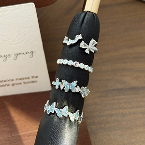 Macro detail of adjustable butterfly and star rings set with blue enamel and zircon