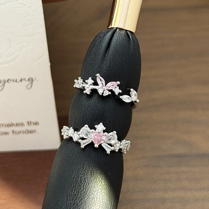 Macro shot of silver rings featuring pink heart and teardrop gemstones with diamond accents