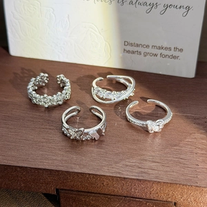 Set of four silver rings with butterfly and flower motifs on a white vintage card