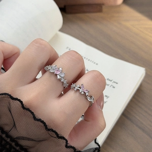 Detail of silver rings featuring pink heart zircon and butterfly motifs on model hands