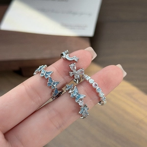 Detail of silver butterfly and moon rings set with blue resin and zircon stones on hand