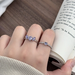 Detailansicht der lila Zirkon-Blumen- und Herzringe am Finger bei sanftem Licht