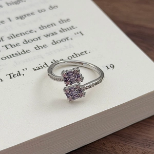Nahaufnahme eines eleganten Blumenrings mit lila und rosa Zirkonia auf einer Buchseite