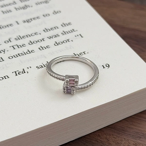 Detail eines überkreuzten Rings mit rosa und lila rechteckigen Zirkoniasteinen