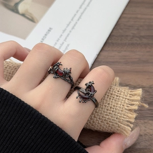 Close-up of gothic black snake-style rings with red crescent stones on a model's hand