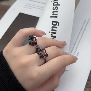 Close-up of gothic black snake ring with red hearts and purple zircon on a model