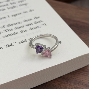Detail eines Bypass-Rings mit lila und rosa Herzsteinen auf einer antiken Buchseite