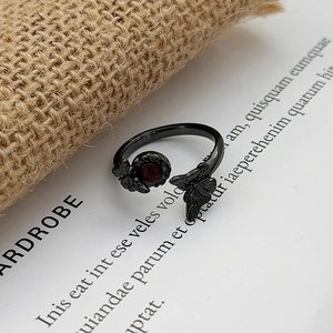 Detailed view of gothic black butterfly ring with a deep red gemstone on vintage paper