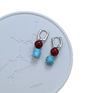 Ethnic style earrings with red agate and irregular turquoise stones on a white tray