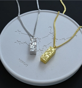 Detailed view of gold and silver rectangular hammered pendants on a Virgo stone tray