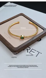 Detail of 55mm open gold-plated bangle with green gemstone and rhombus pattern