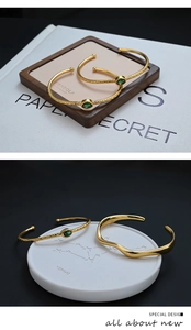 Detailed view of adjustable gold-plated bangle set with green zircon and wavy pattern