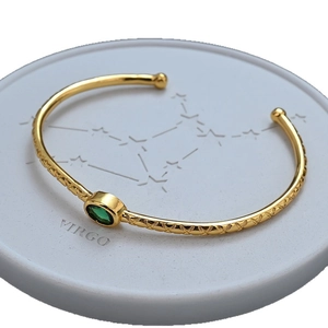 Elegant gold open cuff bracelet with green zircon gemstone and textured lattice pattern