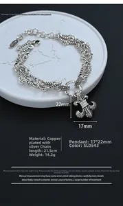 Macro detail of silver fleur-de-lis pendant on multi-layer vintage anchor chain bracelet