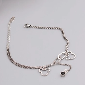 Close-up of silver chain bracelet with round smile charm and vintage metal finish details