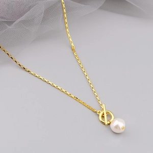 Detail of gold square link necklace featuring a stylish toggle clasp and white pearl pendant