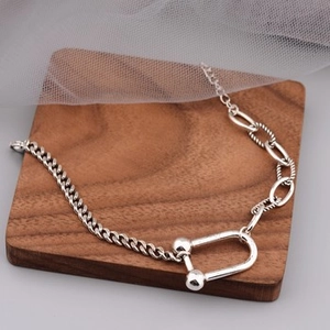 Macro shot of silver metal bracelet with lock pendant and mixed chain on walnut wood