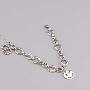 Detailed close-up of a silver chunky chain necklace with a round smiley face pendant charms