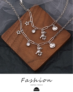 Dettaglio macro del bracciale argento multi-pendente con stelle, strass e orsetti di peluche