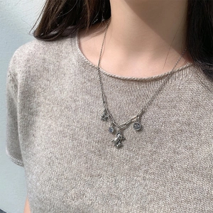 Dettaglio catena argento con ciondoli orsetto e stella indossata da una modella