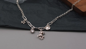 Dettaglio bracciale argento con ciondoli a forma di orsetto, stella e faccina