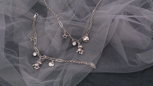 Dettaglio dei ciondoli a forma di orsetto e stella in argento su un bracciale chic