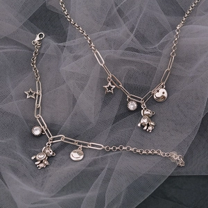 Set gioielli color argento con ciondoli orso e stella su sfondo in rete grigia