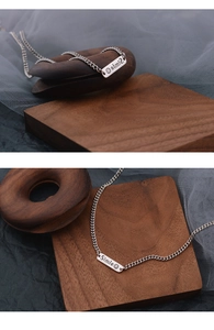 Detail of silver smile pendant necklace with laser engraving on polished metal rectangle