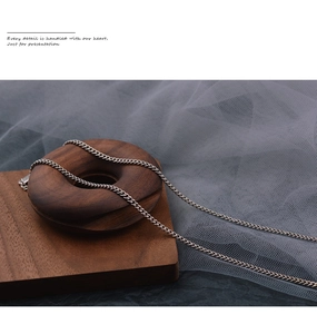 Close-up of minimalist silver smile necklace chain resting on wooden ring display