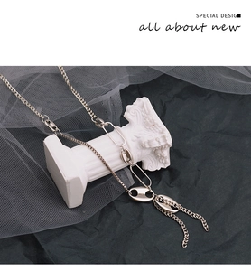 Detail view of silver pig nose chain necklace on a white column with elegant grey tulle