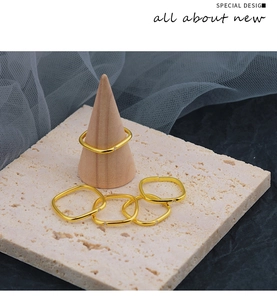 Detaillierte Nahaufnahme minimalistischer goldener quadratischer Ringe auf Holzständer