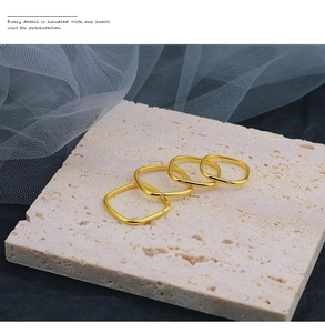 Detailaufnahme von vier minimalistischen goldenen quadratischen Ringen auf Stein