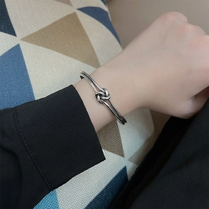 Minimalist silver knot bangle with a vintage woven design for women, shown on wrist