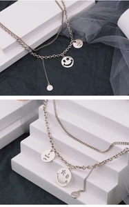 Detail of layered silver chain necklace featuring smiley charms and I love you engraving