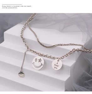 Close-up of silver double-layered chain necklace with star smiley face and I love you charms