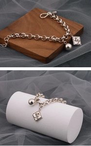 Detailansicht eines silbernen Vintage-Kettenarmbands mit runder Kugel und gravierter Platte